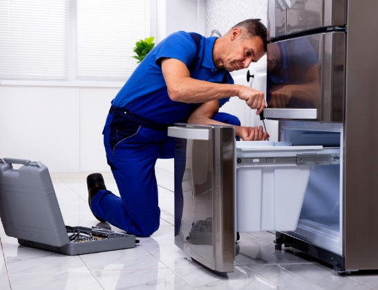 man in blue uniform fixing refrigerator drawer